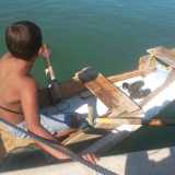 Un'altra inquadratura del ragazzino e del suo piccolo capolavoro di ingegneria nautica